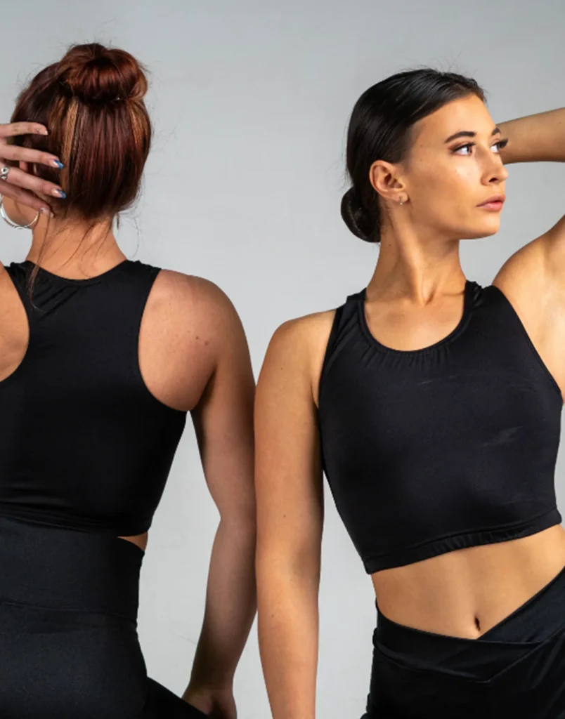 Two dancers modelling black crop tops with high-waisted dance leggings.